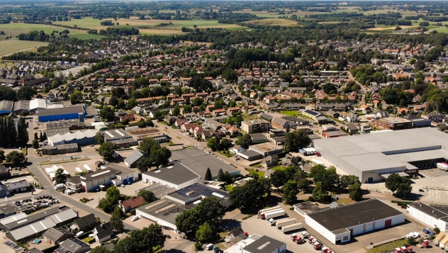 Aerial drone view of business park and city center of Zelhem. Summer blue sky with forest and farmer fields in background. Trucks and trailers in forground on parking area. Gelderland, Doetinchem